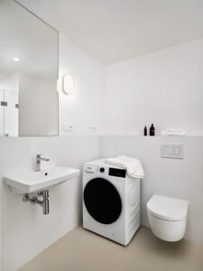 Modern bathroom with a private washer and dryer in a furnished studio apartment at Fellows Jaselská.